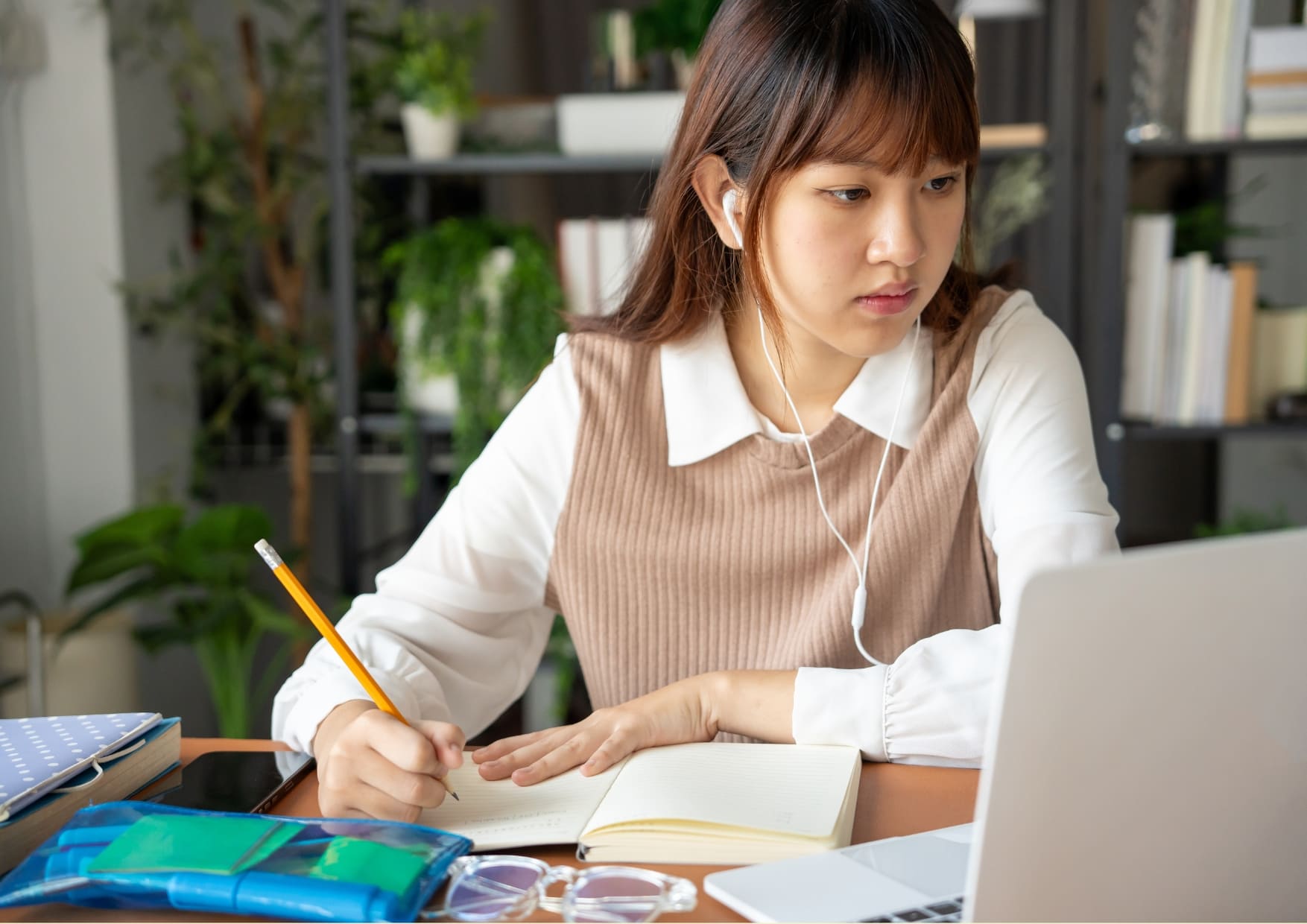 Joven escribiendo notas en su cuaderno mientras estudia inglés